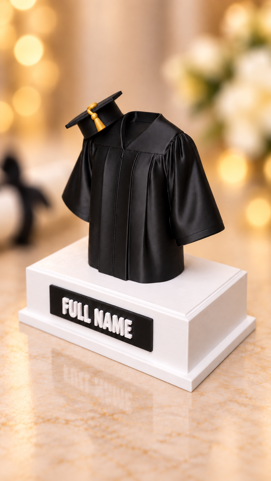 Angled view of black graduation gown keepsake on a white base with personalized name plaque